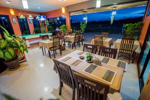 A restaurant with tables and chairs, potted plants, and a pool table. - Samsha Guesthouse (Hua Hin)