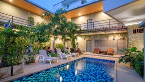 A modern outdoor pool area with lounge chairs, a small waterfall feature, and lush greenery. - Samsha Guesthouse (Hua Hin)