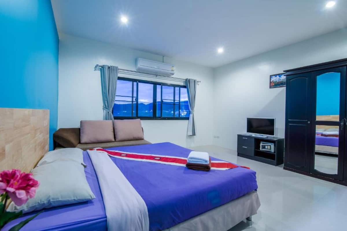 Habitació d'hotel moderna amb un llit gran, televisió, armari i vista a les muntanyes.