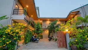 A modern building with a covered entrance, a staircase, and several motorcycles parked outside. - Samsha Guesthouse (Hua Hin)