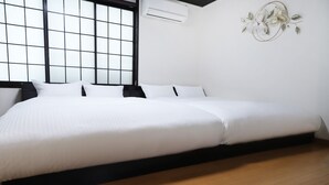Habitació d'hotel moderna amb un llit gran, una finestra amb persianes i un aire condicionat fixat a la paret.