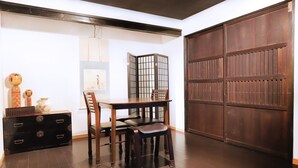 Una habitació amb una taula i cadires de fusta, un taulell negre, un panell decoratiu i una porta de fusta gran.