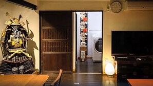 Habitació amb una estàtua tradicional d'un guerrer japonès, una porta de fusta, una rentadora i una televisió.