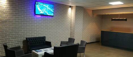 A conference room with a brick wall, a large screen, and a reception desk.