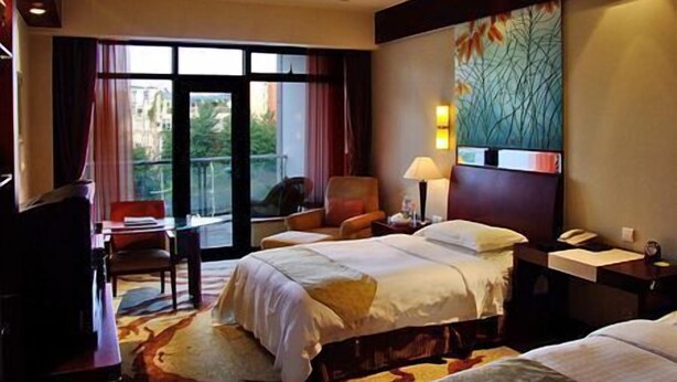 A hotel room with a bed, a desk, a chair, and a large window.