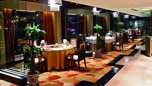 A modern hotel lobby with a round dining table, chairs, and potted plants.