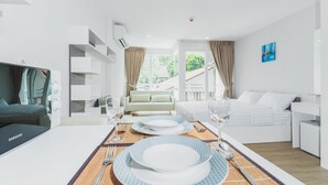 Una habitación de hotel moderna con comedor, cama y vistas al exterior.