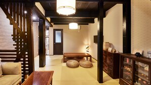 Ein traditionelles japanisches Interieur mit Tatami-Boden, einem niedrigen Holztisch, einer Couch und einer Vitrine mit Glastüren.