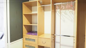 A room with a wooden wardrobe, a bed, and a mirror.