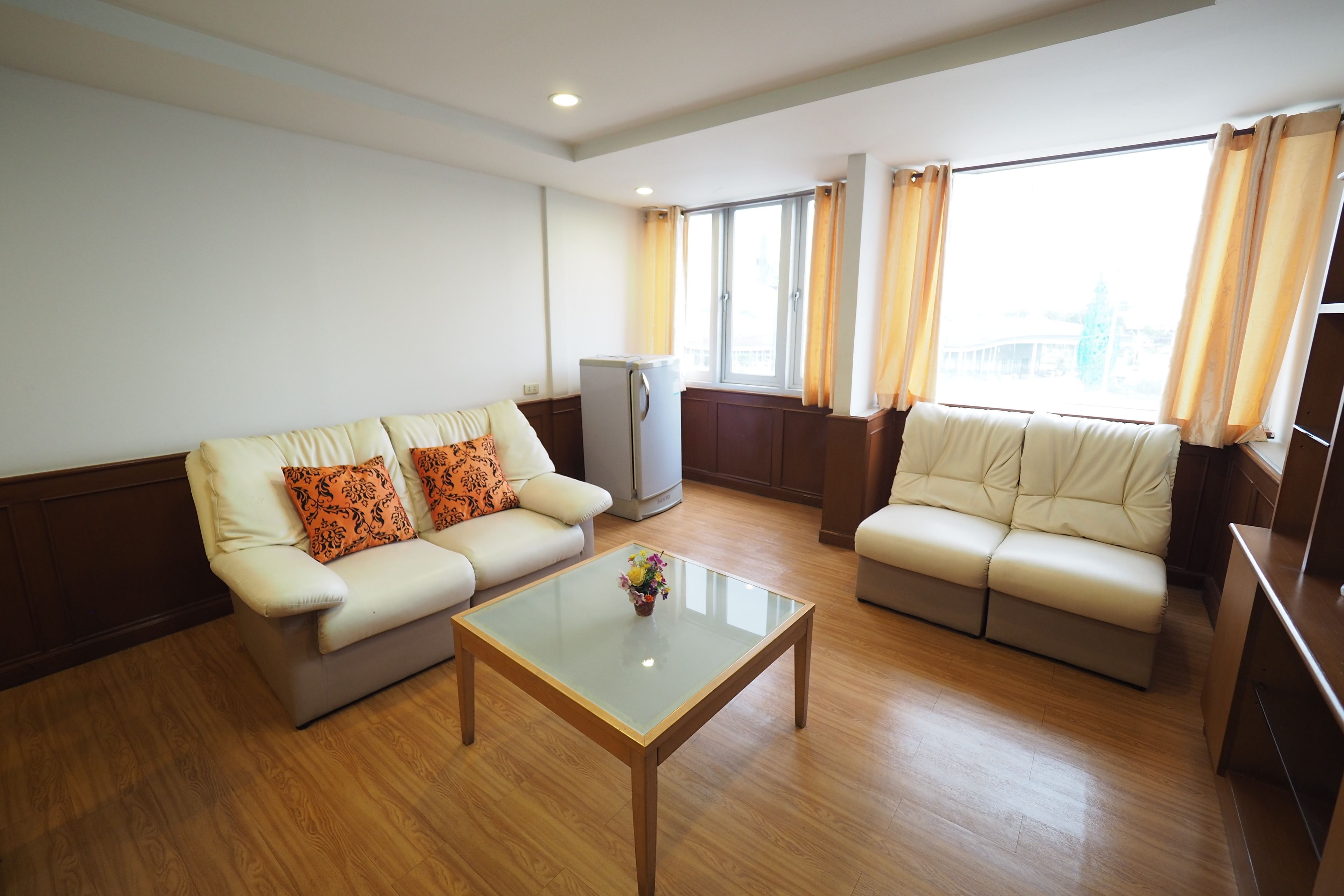 A living room with two sofas, a glass coffee table, and a television.