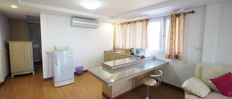 Una cocina compacta con refrigerador, un lavamanos y un taburete de bar.