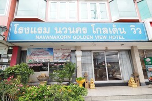The exterior of the Navanakorn Golden View Hotel with a large signboard, potted plants, and traditional Thai decorations.