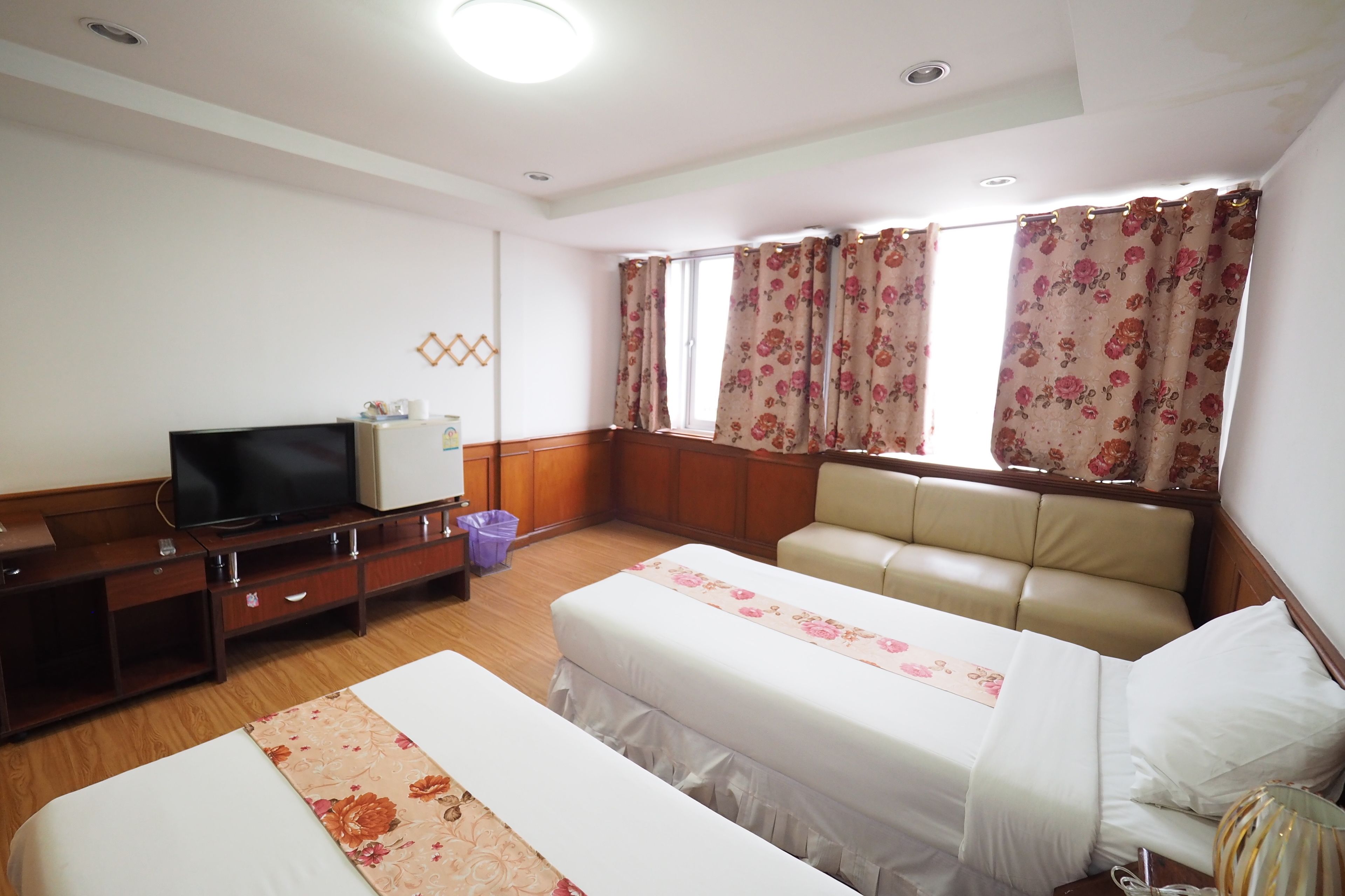 Une chambre d’hôtel avec deux lits, une télévision, un bureau et une fenêtre avec des rideaux.
