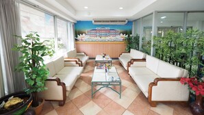 A hotel lobby with a reception desk, seating area, and potted plants. - Navanakorn Golden View (Khlong Luang)
