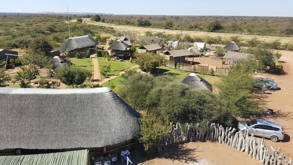 A rural area with thatched-roof houses, a dirt road, and sparse vegetation. - Makumutu Lodge & Campsite (Orapa)