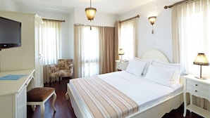 Habitación de hotel con una cama grande, un escritorio con silla, televisión y dos lámparas de noche.