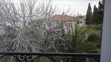 Un balcó amb vista a un edifici amb teulada vermella, envoltat d'arbres i vegetació.