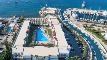 An aerial view of a resort with a swimming pool, multiple boats, and a marina.