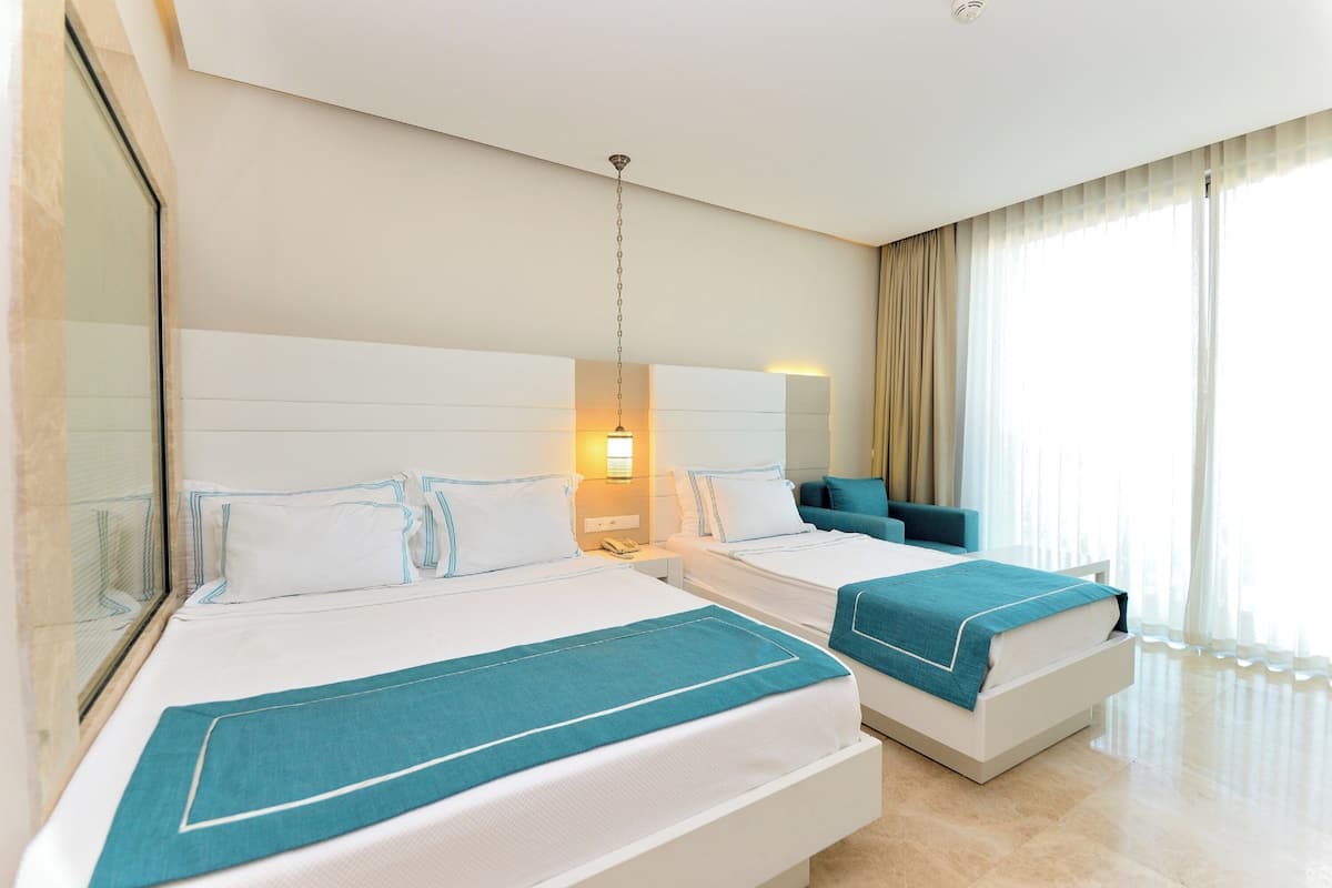 A hotel room with two beds, a large window with curtains, and a modern design.