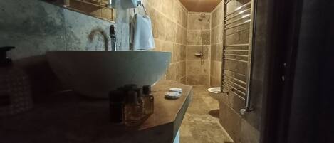 Un baño con un lavamanos grande, una toalla colgada en la pared y una zona de ducha.