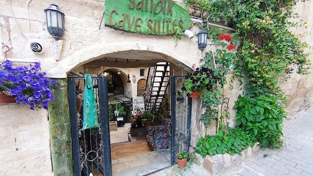 An entrance to a cave-like structure with a sign reading "Sanok Cave Suites." - Sandik Cave Hotel (Ürgüp)
