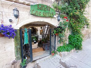 An entrance to a cave-like structure with a sign reading "Sanok Cave Suites." - Sandik Cave Hotel (Ürgüp)