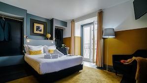 Een hotelkamer met een bed, een bureau, een stoel, een lamp en uitzicht op buiten.