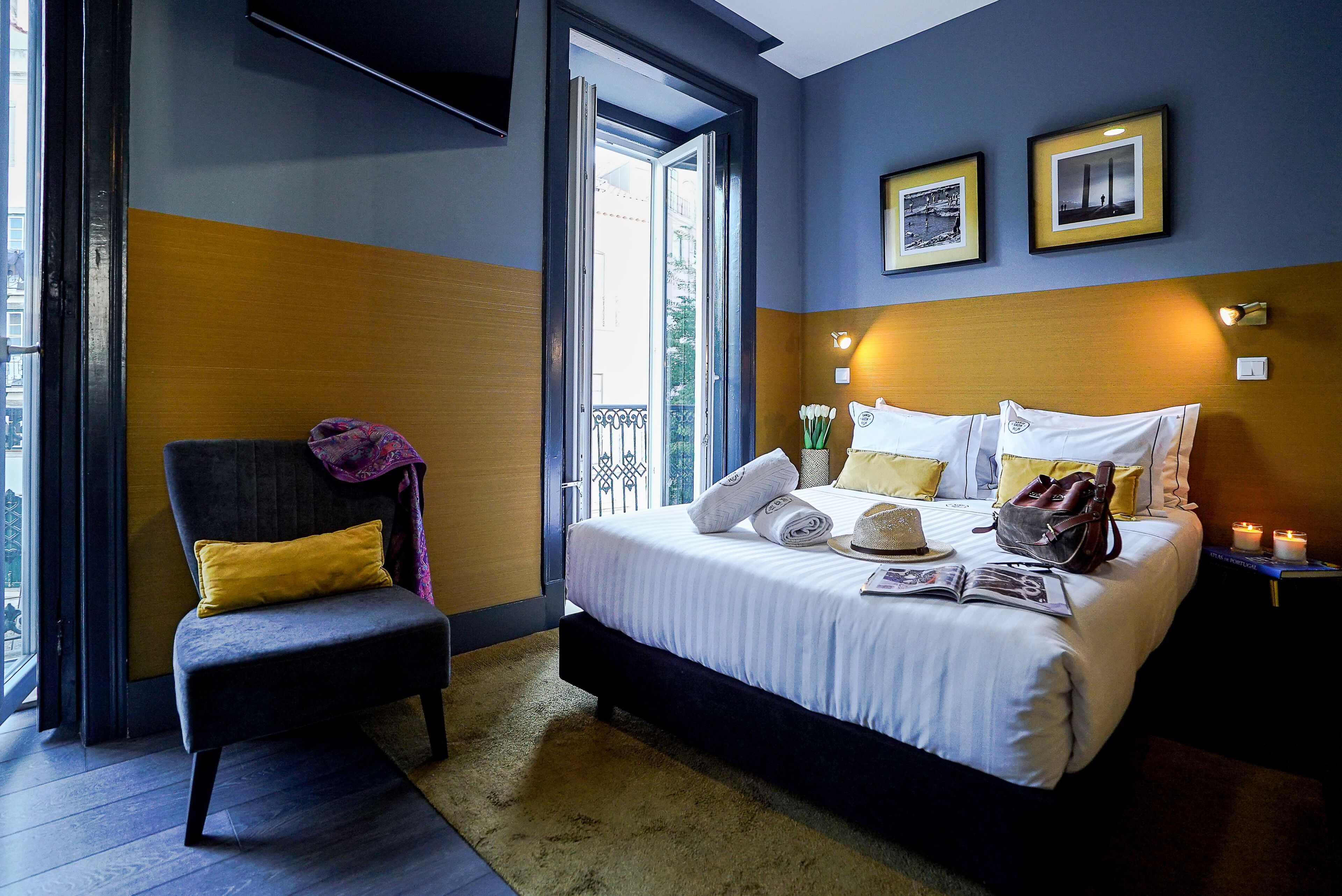 A hotel room with a bed, a chair, a window, and a door.