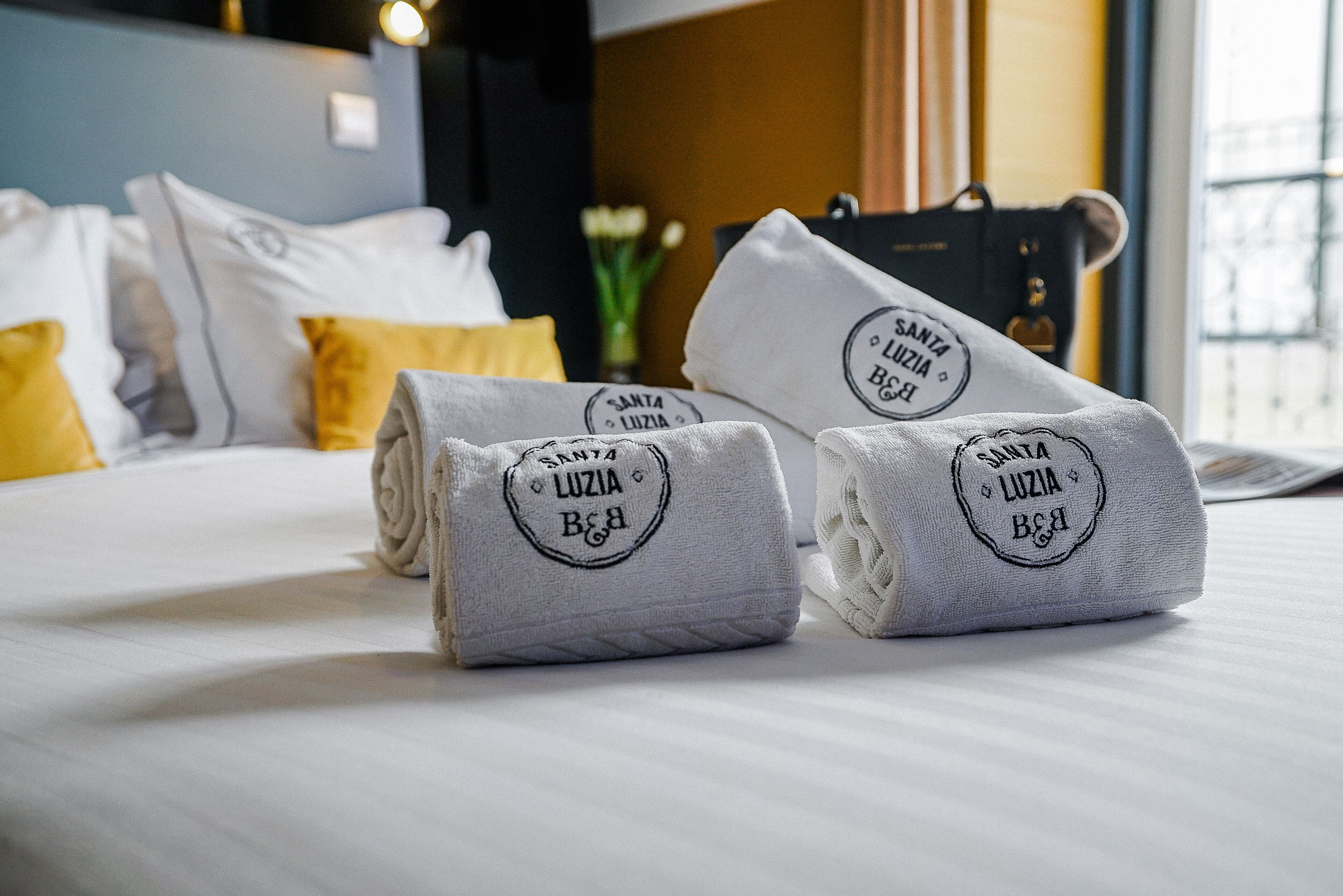 Neatly folded towels with a logo on a bed in a hotel room.