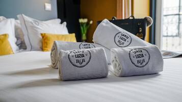 Neatly folded towels with a logo on a bed in a hotel room.