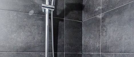 A shower with a handheld showerhead and a wall-mounted control.