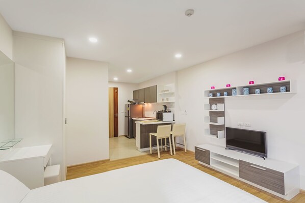 A modern hotel room with a bed, a TV, a desk, and a kitchenette. - Condo in Kata in Ozone - A519 (Karon)