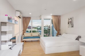 A modern hotel room with a large bed, a sofa, a desk, and a balcony with a view. - Condo in Kata in Ozone - A519 (Karon)