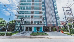 A modern hotel with multiple floors, a prominent entrance, and a parking area. - Condo in Kata in Ozone - A519 (Karon)