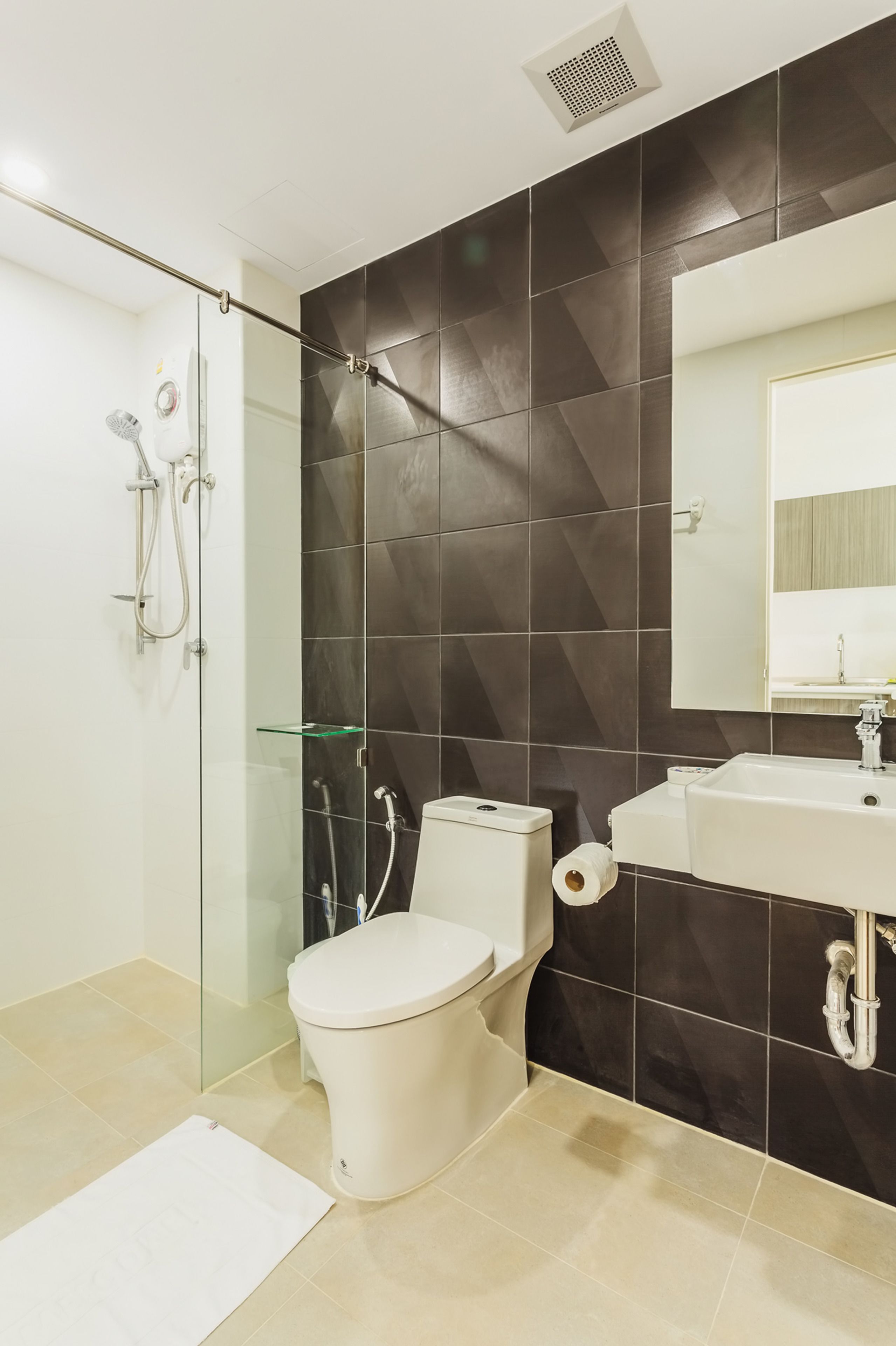 A modern bathroom with a glass shower enclosure, a white toilet, and a sink with a mirror above it.