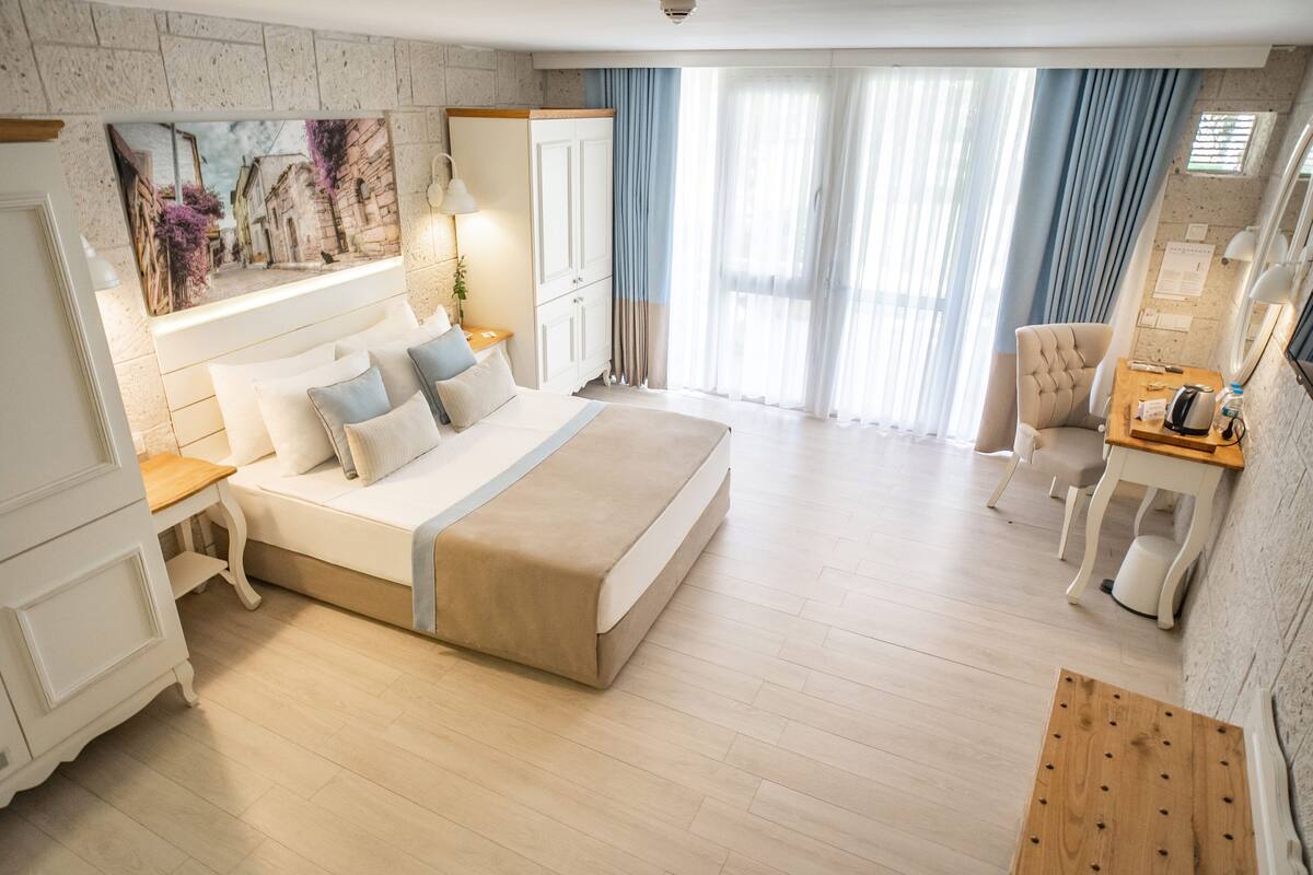 Ein Hotelzimmer mit einem großen Bett, einem Schreibtisch, einem Sessel und einem Gemälde an der Wand.