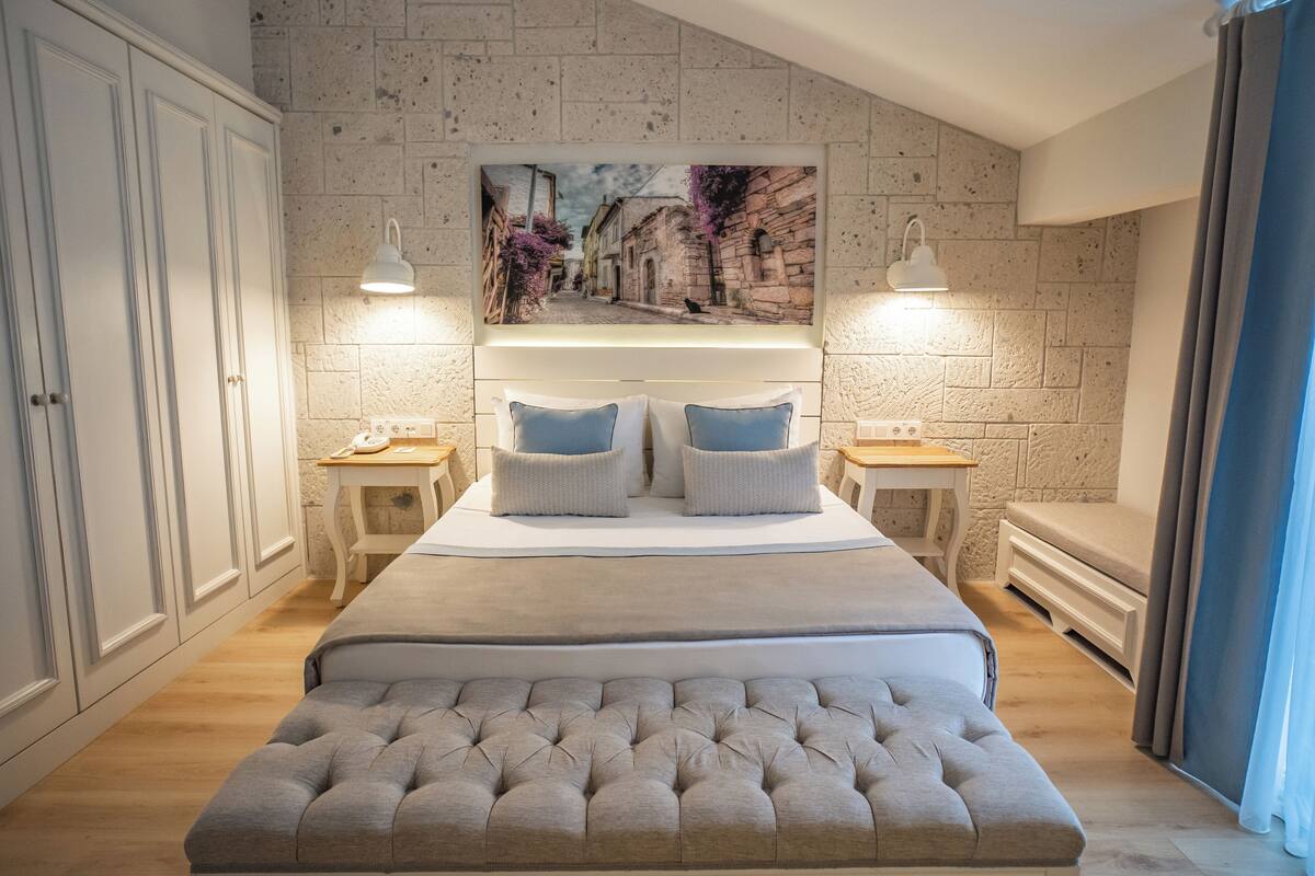 Ein Schlafzimmer mit einem großen Bett, zwei Nachttischen, einer Bank und einem Wandbild.