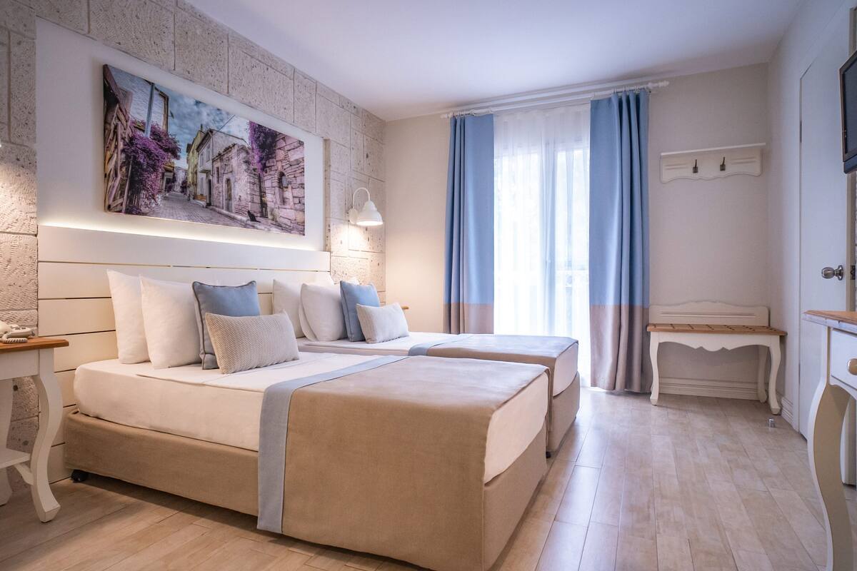 Ein modernes Hotelzimmer mit zwei Betten, einem großen Gemälde an der Wand, einem Schreibtisch und einem Fernseher.