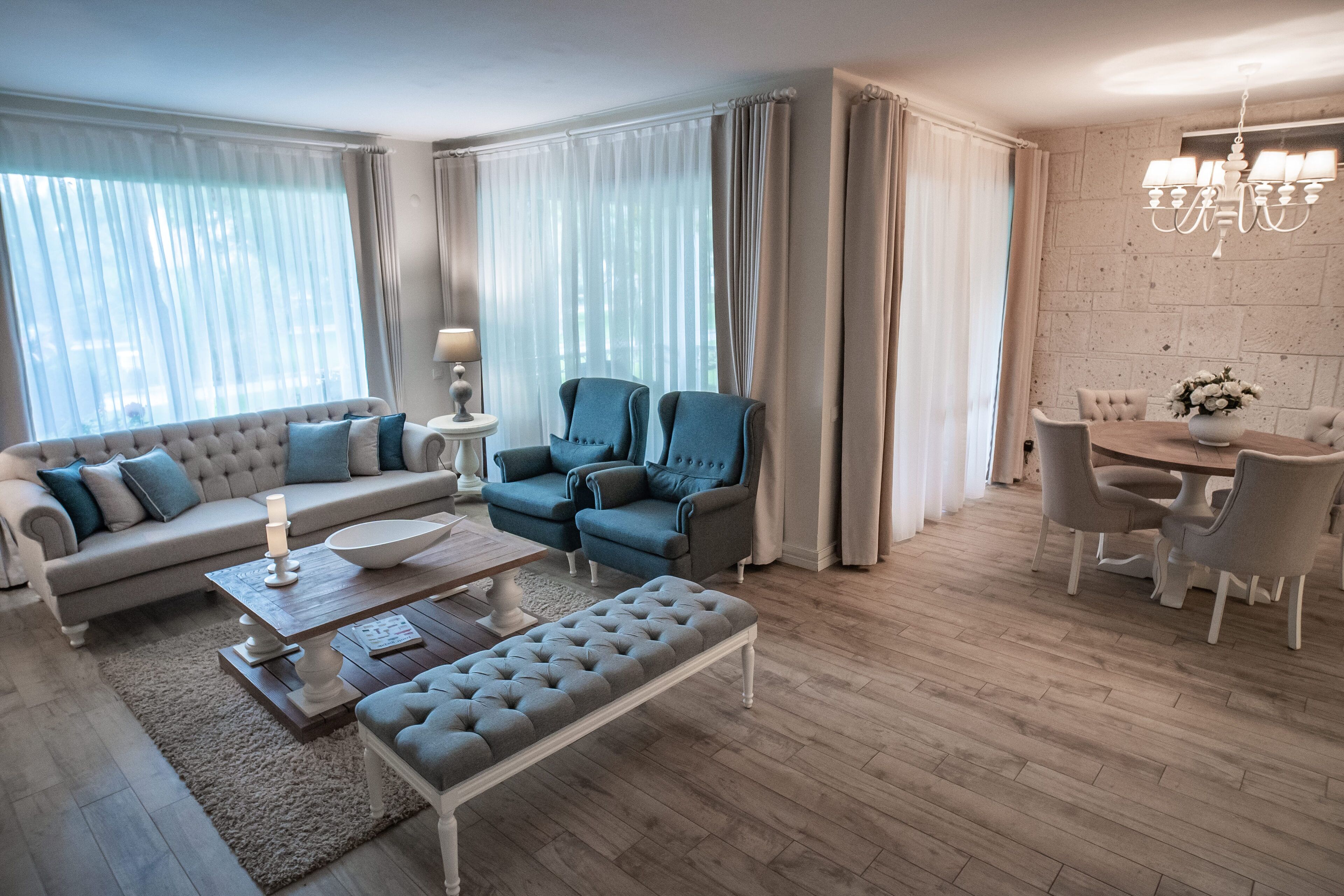 Una sala de estar moderna con un sofá, dos sillones, una mesa de centro y una mesa de comedor con sillas.