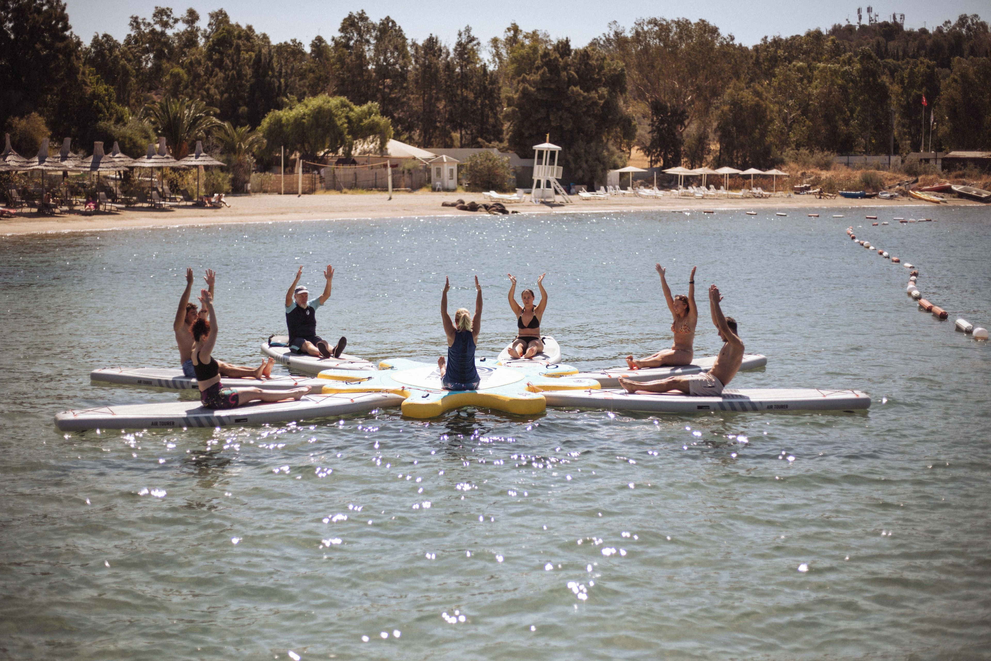 Eine Gruppe von Menschen steht auf Paddleboards in ruhigem Wasser.
