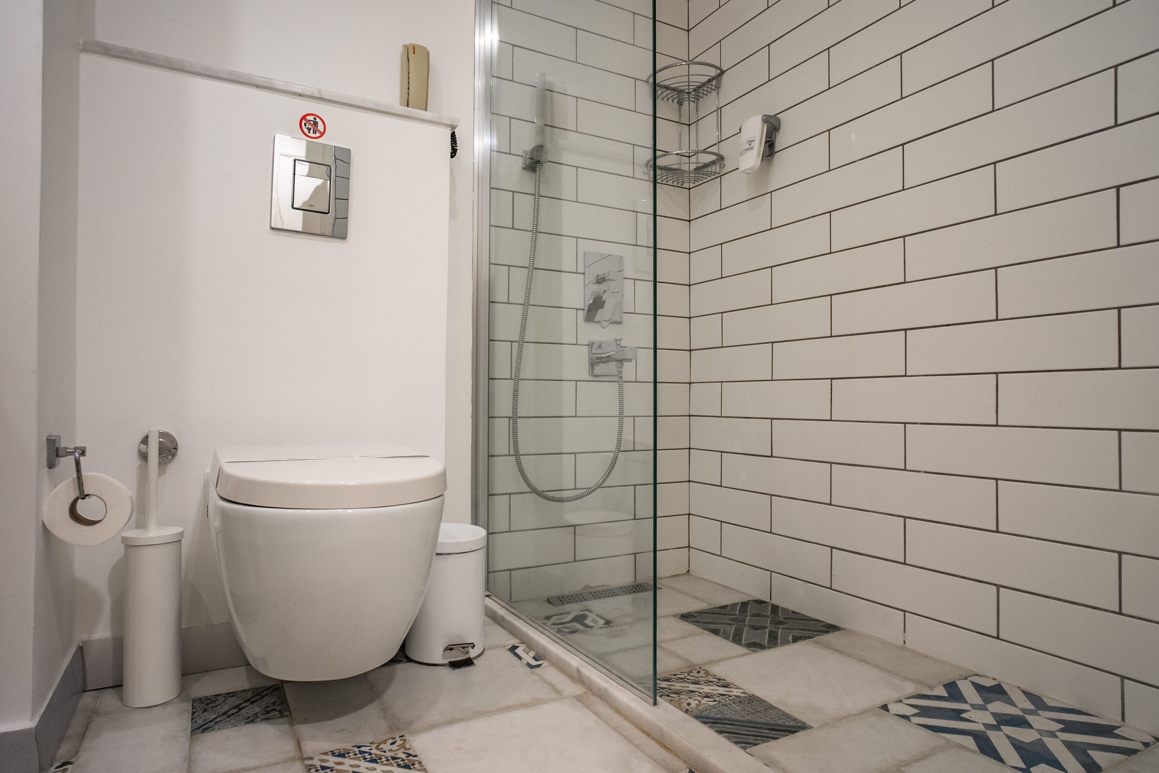 Un baño con inodoro, bidé y cabina de ducha con mampara de vidrio.