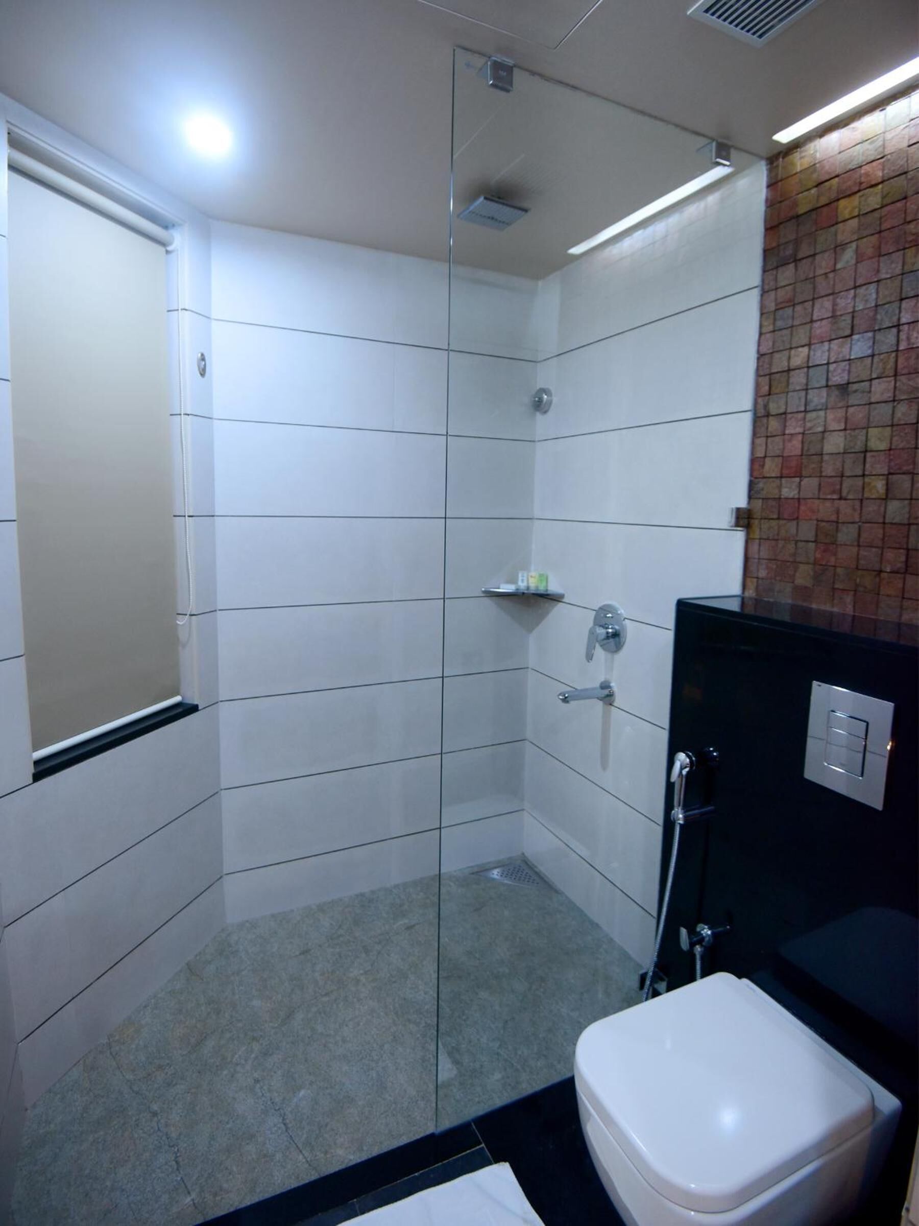 A modern bathroom with a glass shower enclosure, a white toilet, and a black sink.