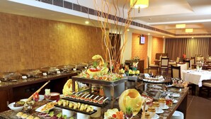 Buffet com diversos alimentos e área de refeições com mesas e cadeiras.