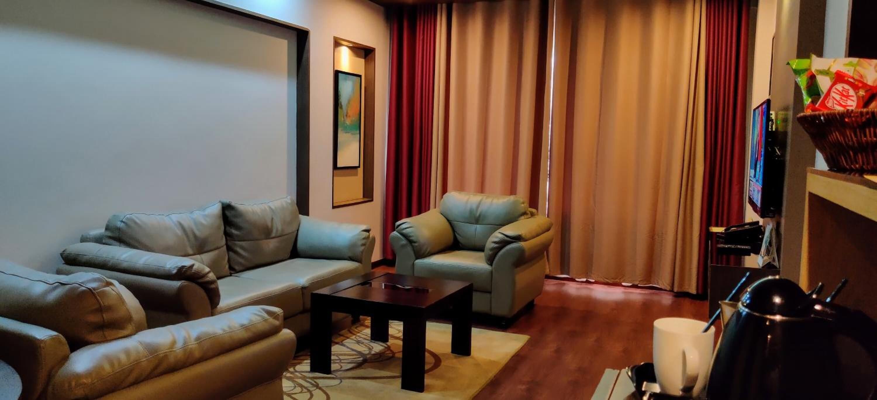 A living room with a sofa, armchair, coffee table, and a television.