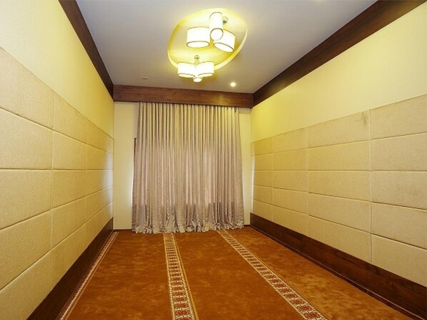 A hallway with beige walls, a patterned carpet, and a ceiling light fixture.