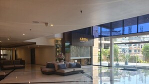 Um hall amplo com design moderno, com área de estar com sofás e um grande balcão de vidro para 'ARIBA PERFUMES & GIFTS'.