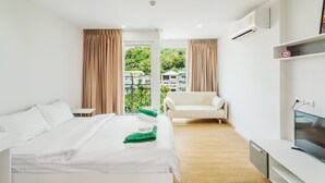 Een hotelkamer met een bed, een stoel, een televisie en een balkon met gordijnen.