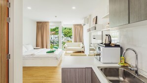 Een compacte hotelkamer met een bed, kitchenette en uitzicht op groen.