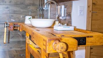 Un banco de trabajo de madera con un lavabo, un dispensador de toallas y un espejo arriba.