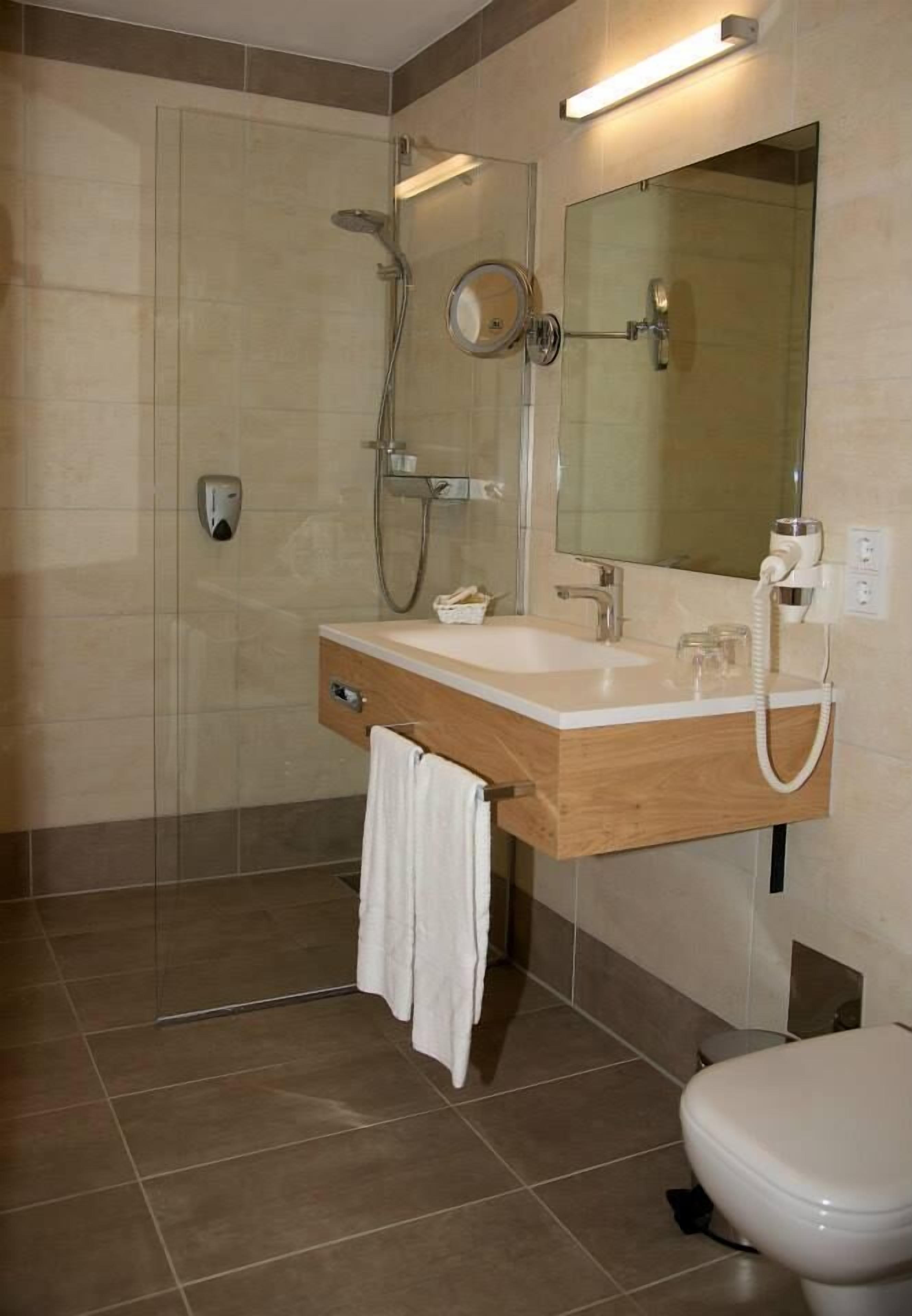 Un baño moderno con ducha, lavabo con espejo e inodoro.